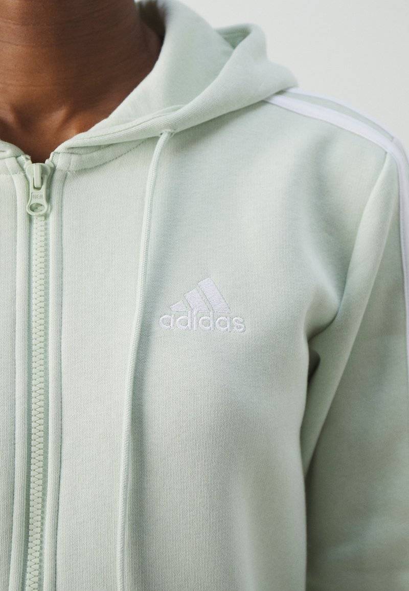 adidas Sportswear adidas Sportswear ESSENTIALS 3 STRIPES FULL ZIP HOODIE - Zip-up sweatshirt - linen green Valentinstagsangebot